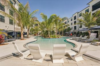 A pool surrounded by palm trees and white chairs